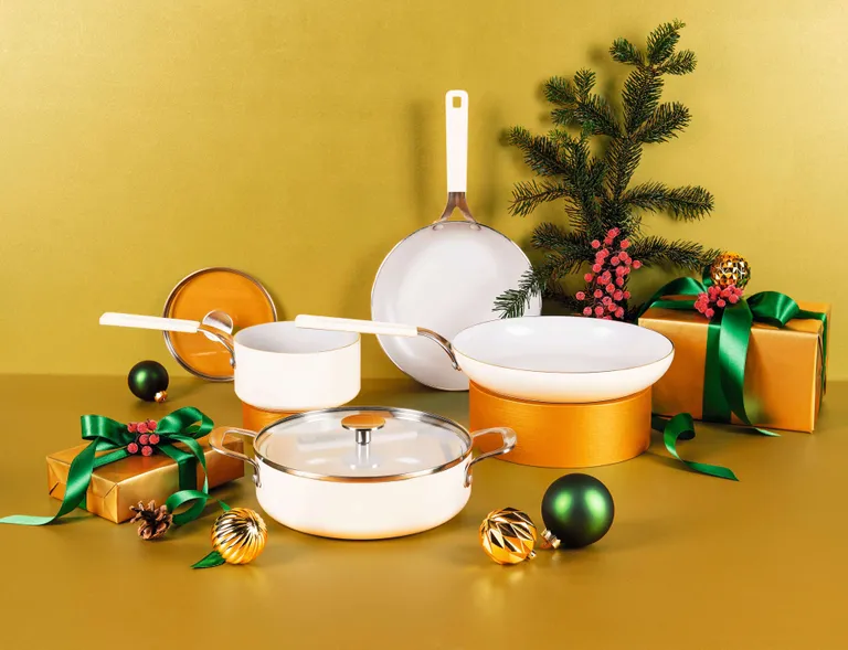 Mehrere verschiedene beige Pfannen, Töpfe & Bräter neben weihnachtlich verpackten Geschenken