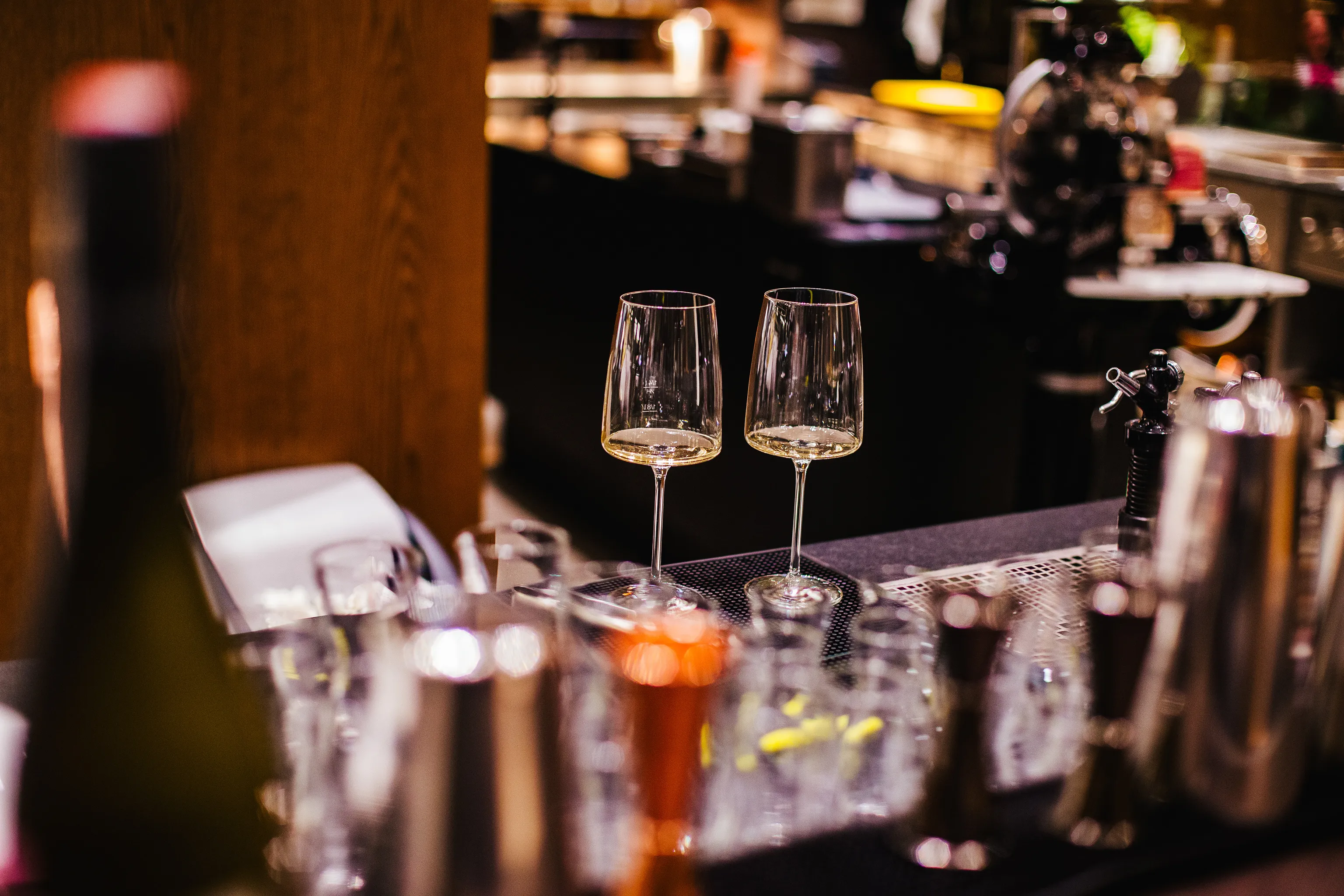2 Weingläser mit einer Weißweinprobe stehen an der Bar des das Mezzanin