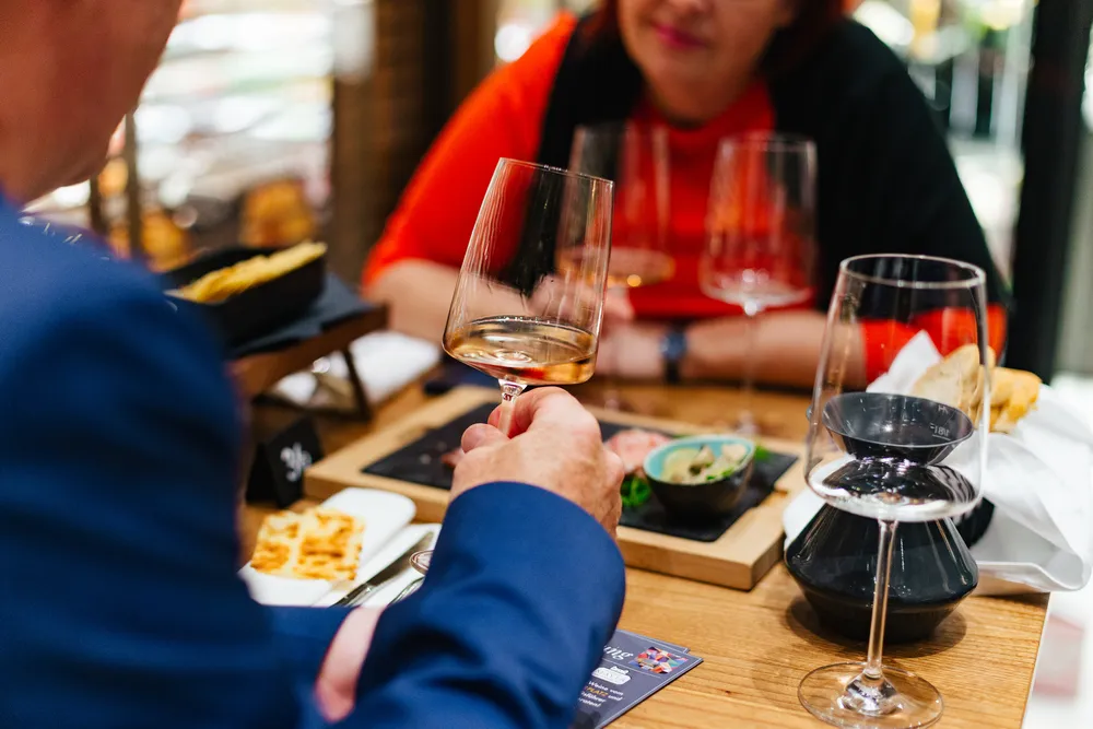 2 Personen sitzen an einem Tisch im das Mezzanin und verkosten Wein