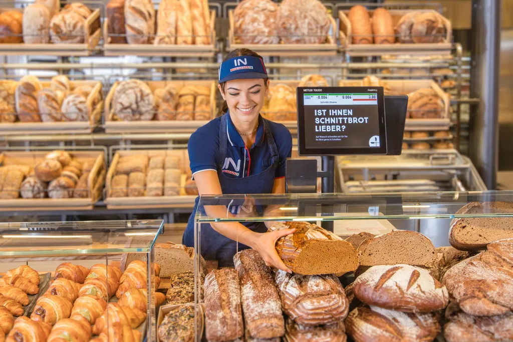 Eine Mitarbeiterin legt einen Laib Brot in die Vitrine der Brotabteilung