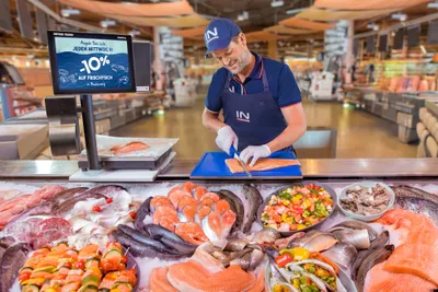 Ein Mitarbeiter portioniert frischen Fisch an der Fischtheke