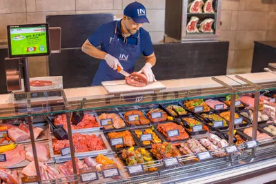 Ein Mitarbeiter portioniert frisches Fleisch an der Fleischtheke