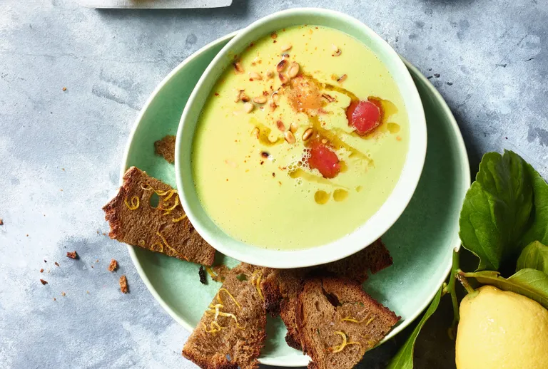 Cremige Avocadosuppe mit gerösteten Brotwürfeln, Pinienkernen, Olivenöl und frischer Zitrone