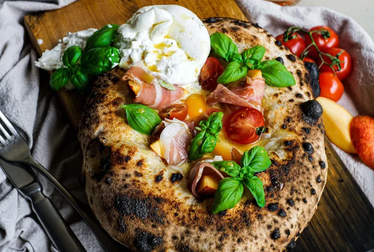 Steinofenpizza mit Burrata, Prosciutto, Pfirsich, Basilikum und Cherrytomaten
