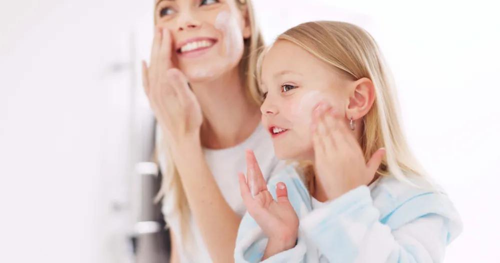Mutter und Tochter tragen gemeinsam Gesichtscreme auf und genießen ihre tägliche Hautpflegeroutine