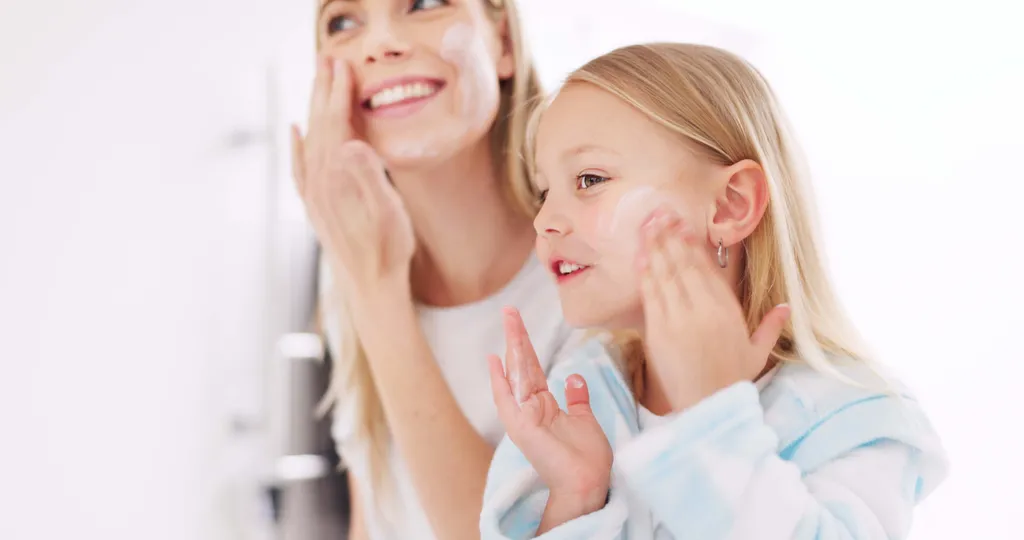 Mutter und Tochter tragen gemeinsam Gesichtscreme auf und genießen ihre tägliche Hautpflegeroutine