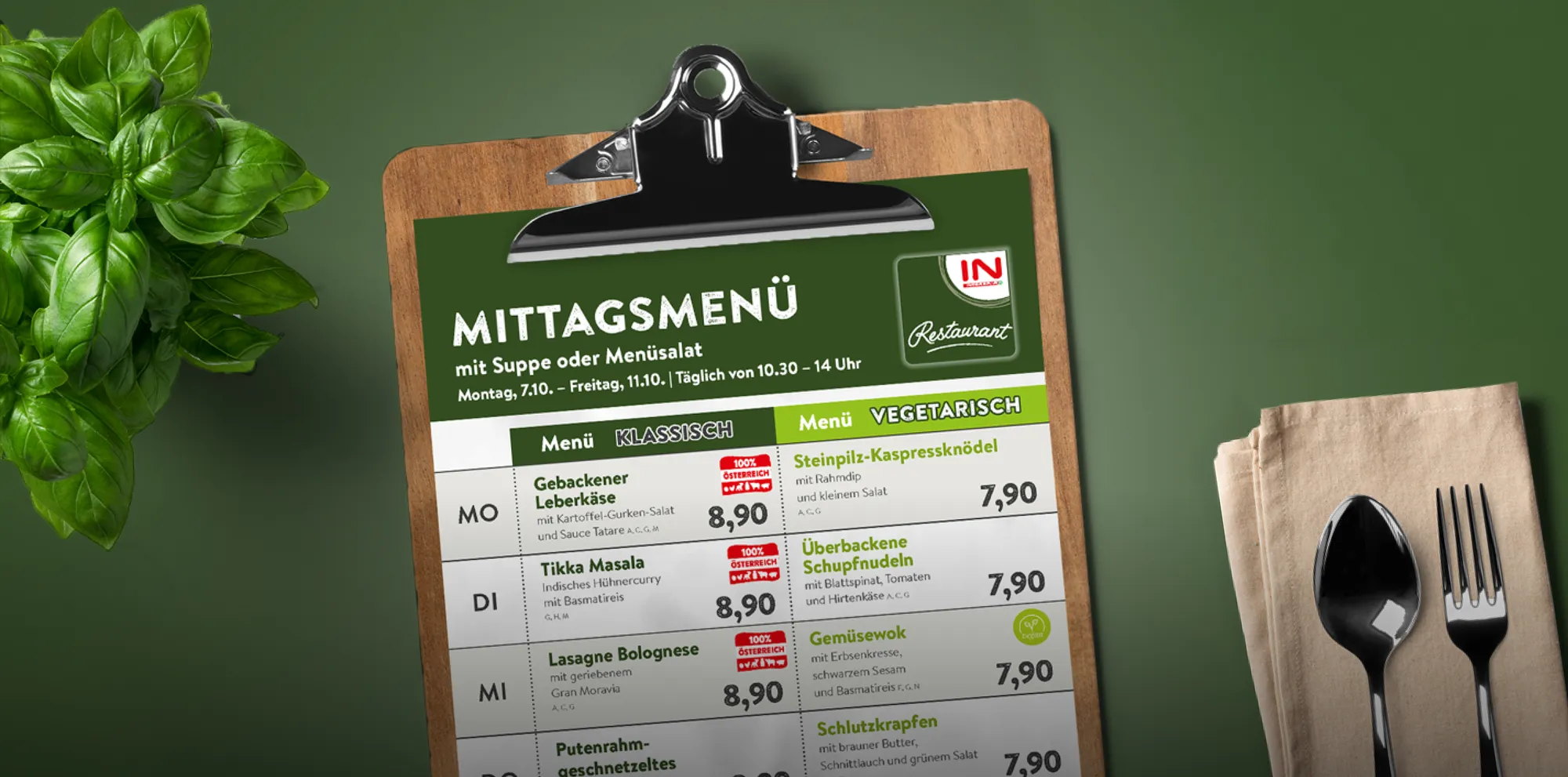 Ein symbolischer INTERSPAR-Menüplan auf einem Klemmbrett vor einem grünen Hintergrund