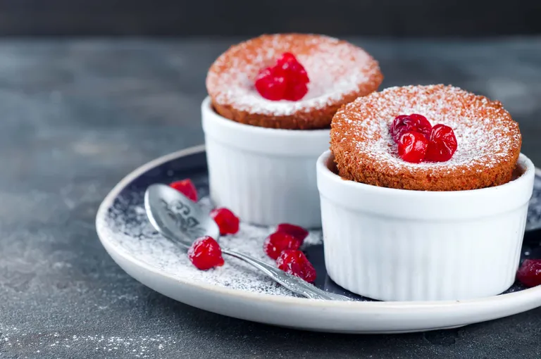 Zwei luftige Himbeer-Soufflés mit Puderzucker und frischen Himbeeren