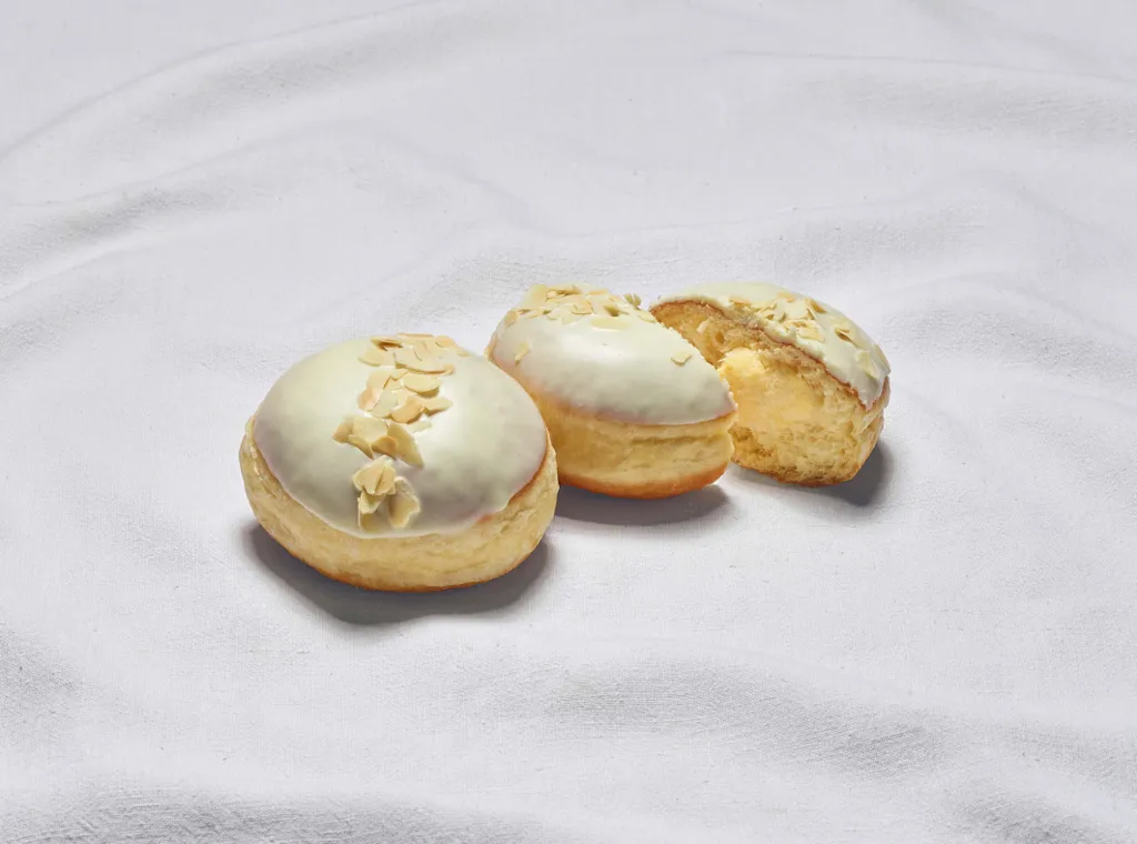 Zwei Vanille-Krapfen aus der INTERSPAR-Backstube legen auf einem weißen Tuch wobei einer der Krapfen mittig halbiert ist
