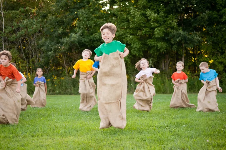 Kinder beim Sackhüpfen in einem Garten