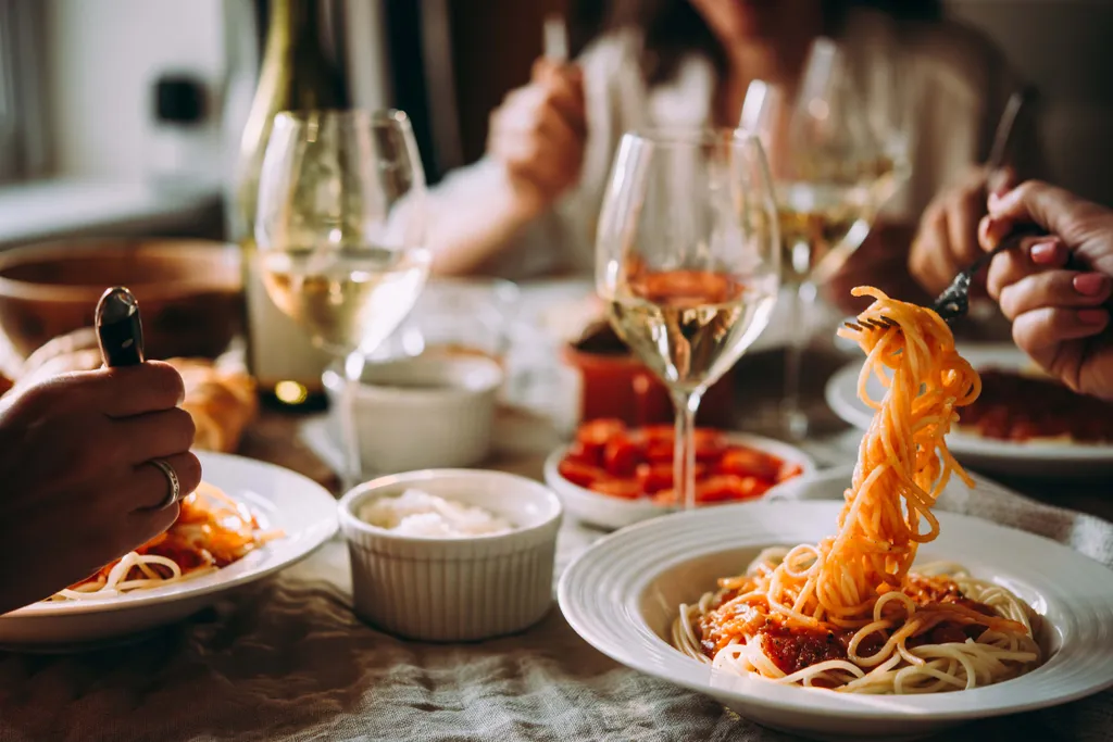 Gemütliches Abendessen mit Spaghetti, Tomatensauce und Weißwein in geselliger Runde