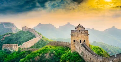 Chinesische Mauer schlängelt sich durch grüne Berge unter dramatischem Himmel