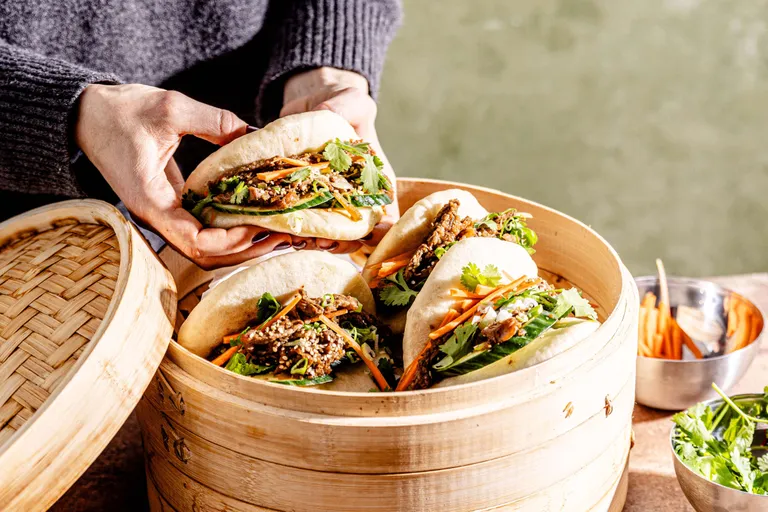 Gedämpfte Bao Buns mit asiatisch mariniertem Rindfleisch, Gemüse und frischen Kräutern