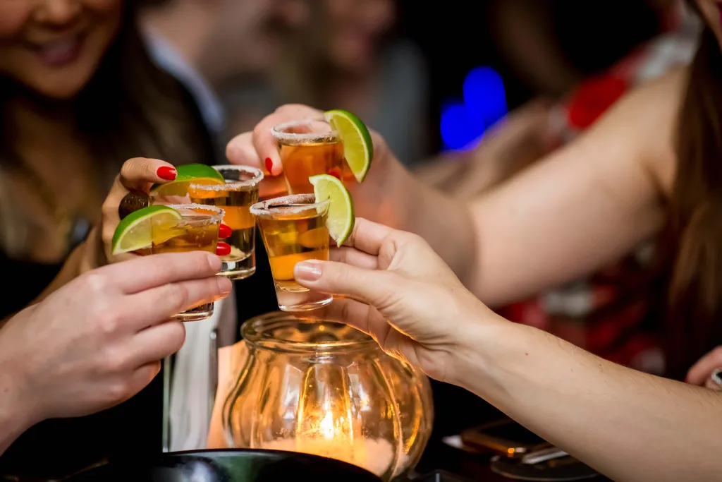 Freunde stoßen mit Tequila-Shots und Limettenspalten an