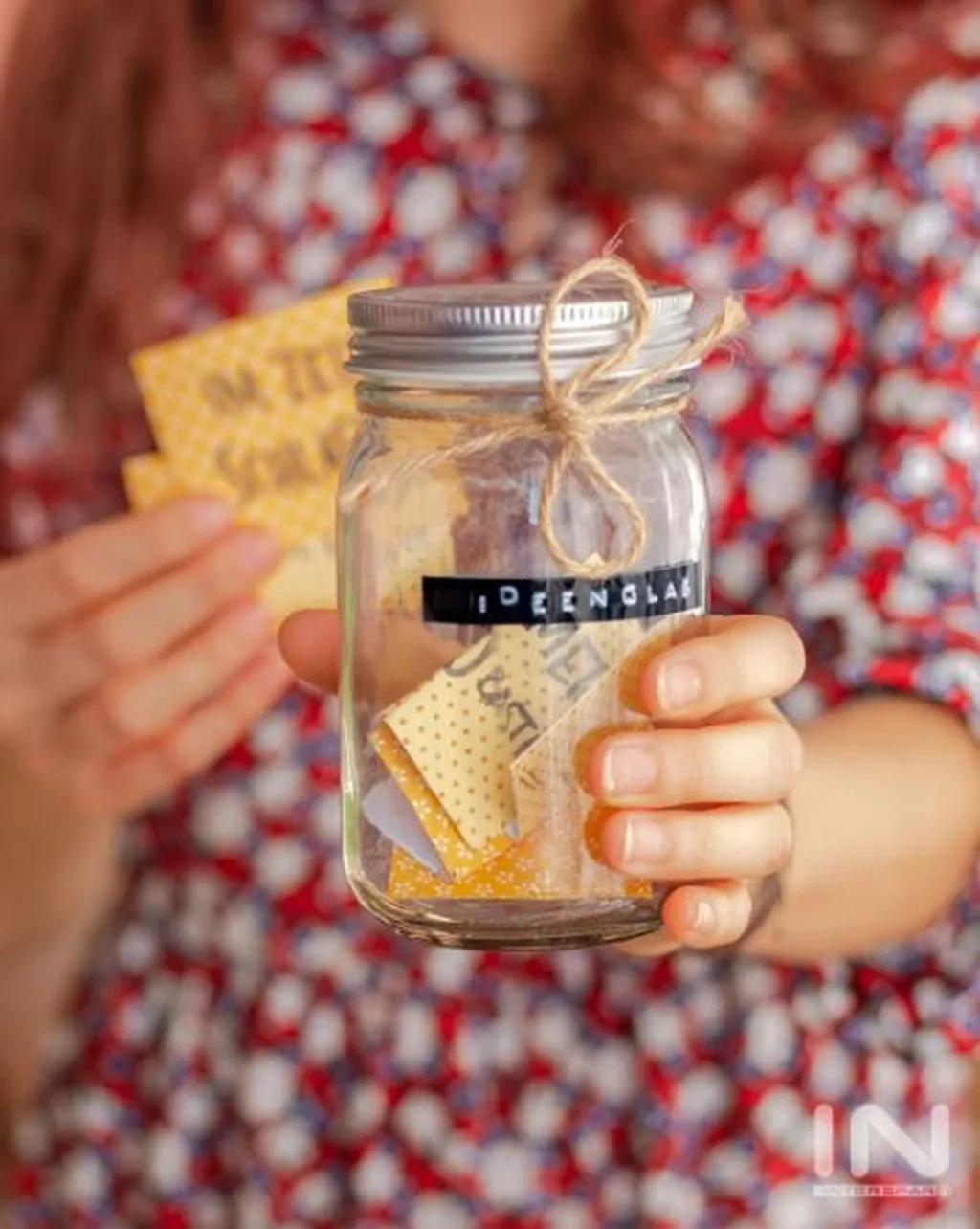 Ein Mädchen hält ein Marmeladeglas mit der Aufschrift "Ideenglas" in die Kamera