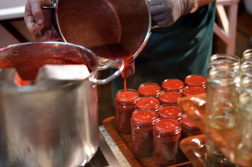 Heiße Marmelade wird direkt aus dem Topf in saubere Einmachgläser gefüllt