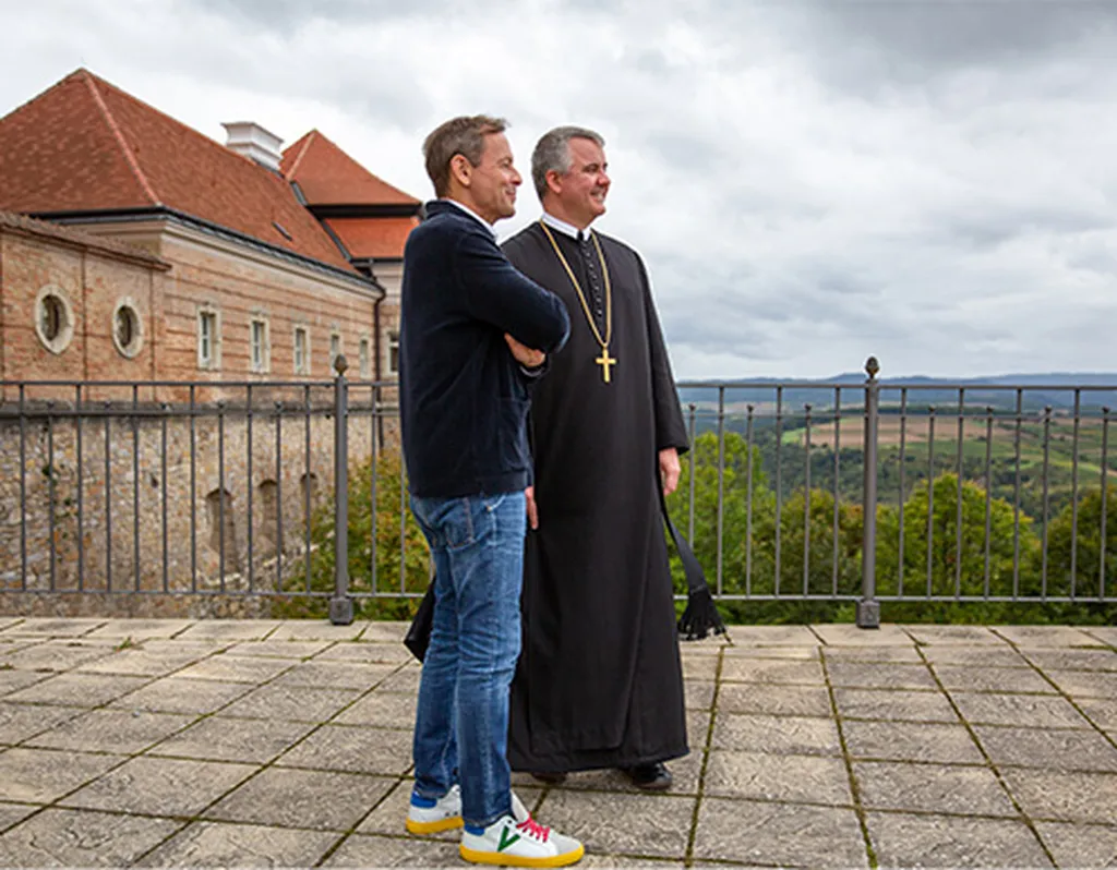 Fritz Miesbauer und Patrick Schöder von der Seite auf dem Benediktinerstift bei bewölktem Himmel.