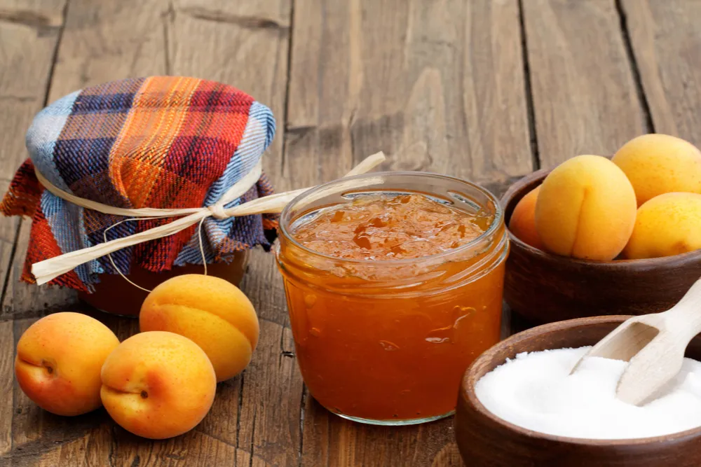 Aprikosen und Marillenmarmelade im Glas auf Holztisch