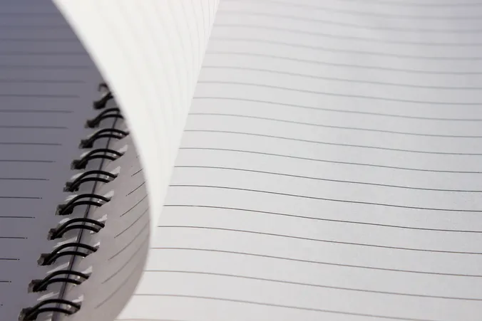 Nahaufnahme eines linierten Blocks aus Papier, wie eine Seite umgeblättert wird
