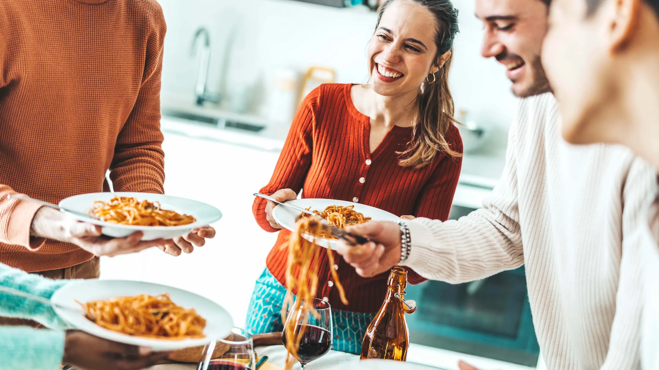 Freunde servieren frisch gekochte Pasta und genießen ein gemeinsames Essen in der Küche