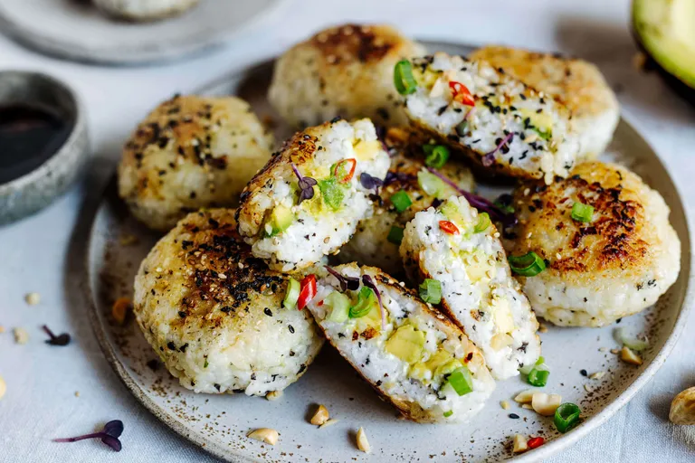 Knusprig gebratene Onigiri mit Avocado und Reisfüllung auf einem Teller angerichtet