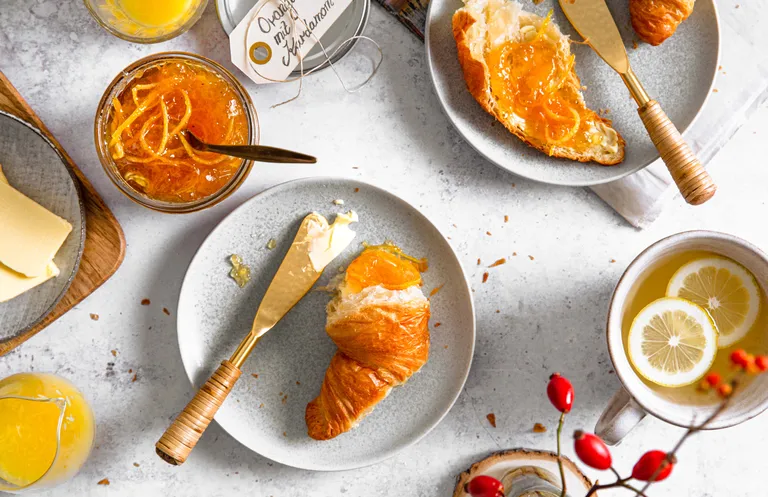 Croissant mit hausgemachter Orangen-Kardamom-Marmelade und einer Tasse Tee zum Frühstück