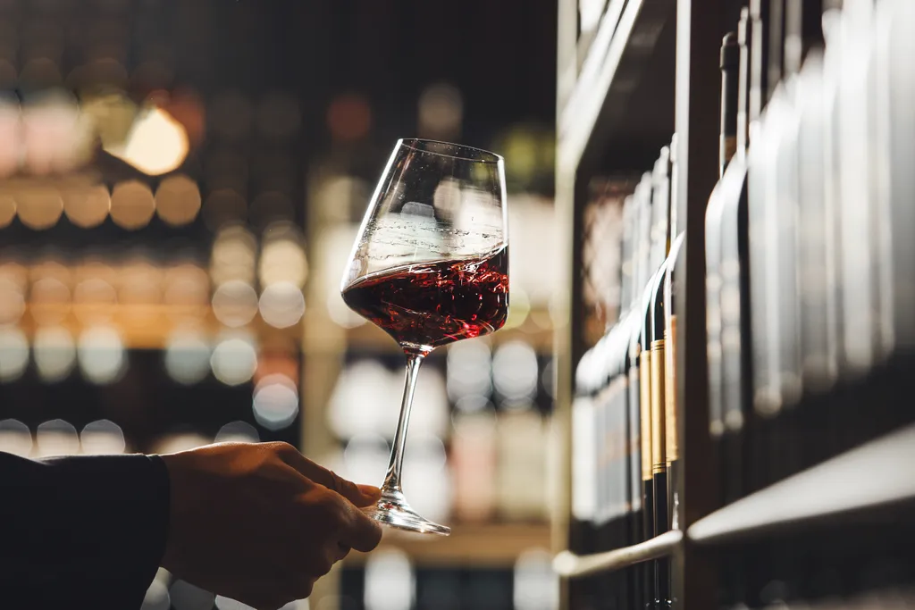 Eine Person hält ein Glas Rotwein in der Hand.