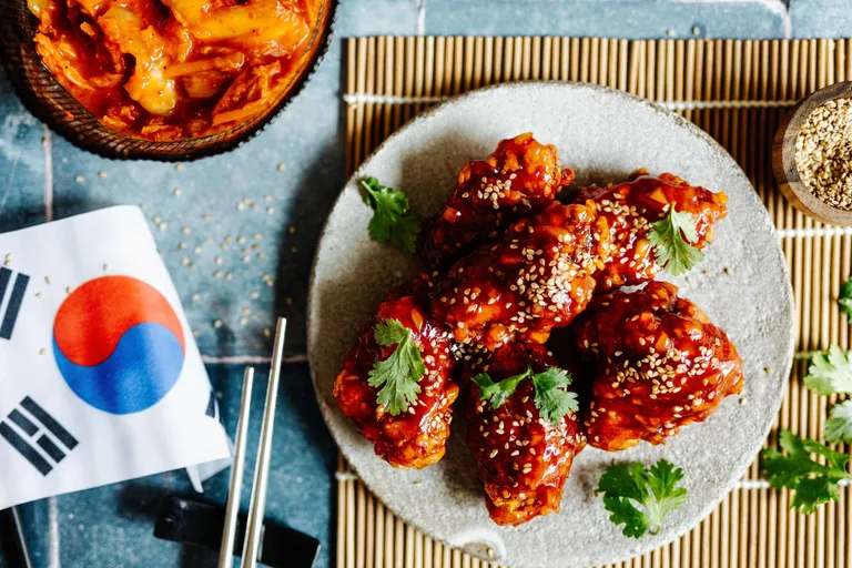 Knusprige koreanische Chicken Wings mit scharfer Gochujang-Glasur, Sesam und Koriander