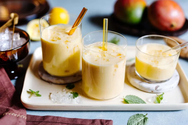Erfrischender Mango Lassi in Gläsern mit frischer Minze und Eis