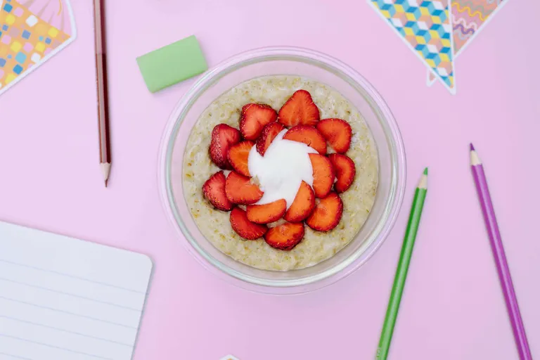 Schüssel mit cremigem Porridge, frischen Erdbeeren und Joghurt als gesundes Frühstück