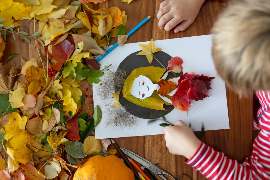 Ein Junge legt Herbstblätter als Collage auf