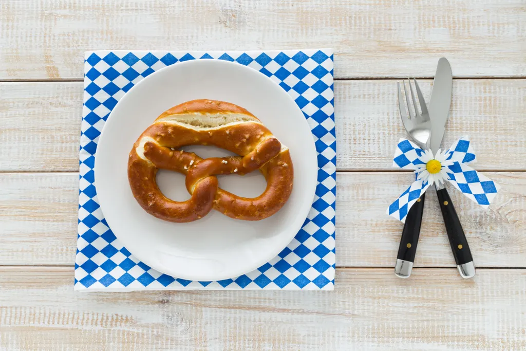 Tischdekoration zum Thema Oktoberfest mit Breze und Besteck und karierter Serviette