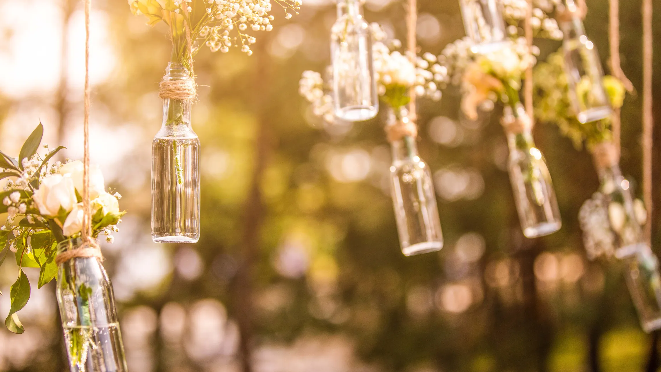 Kleine Flaschen mit Blumensträußen hängen von den Ästen eines Baumes