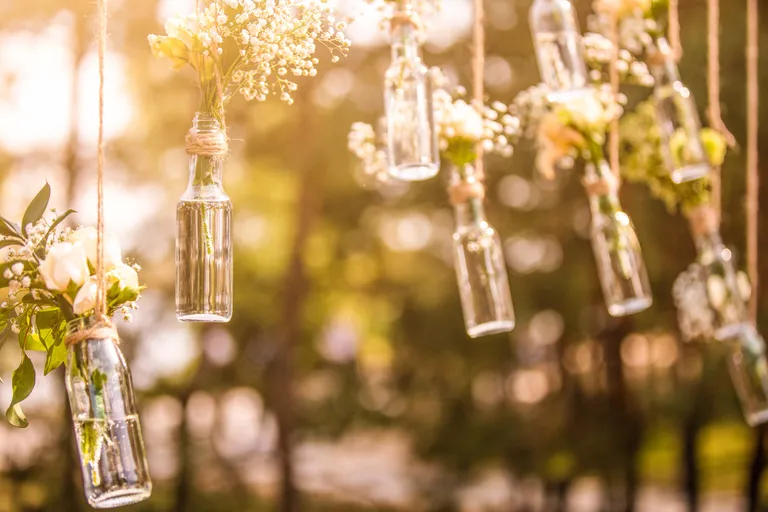 Kleine Flaschen mit Blumensträußen hängen von den Ästen eines Baumes