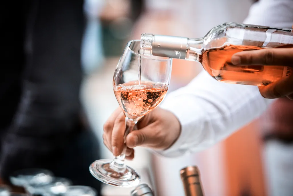 Es ist zu sehen, wie ein Roséwein eingeschenkt wird.