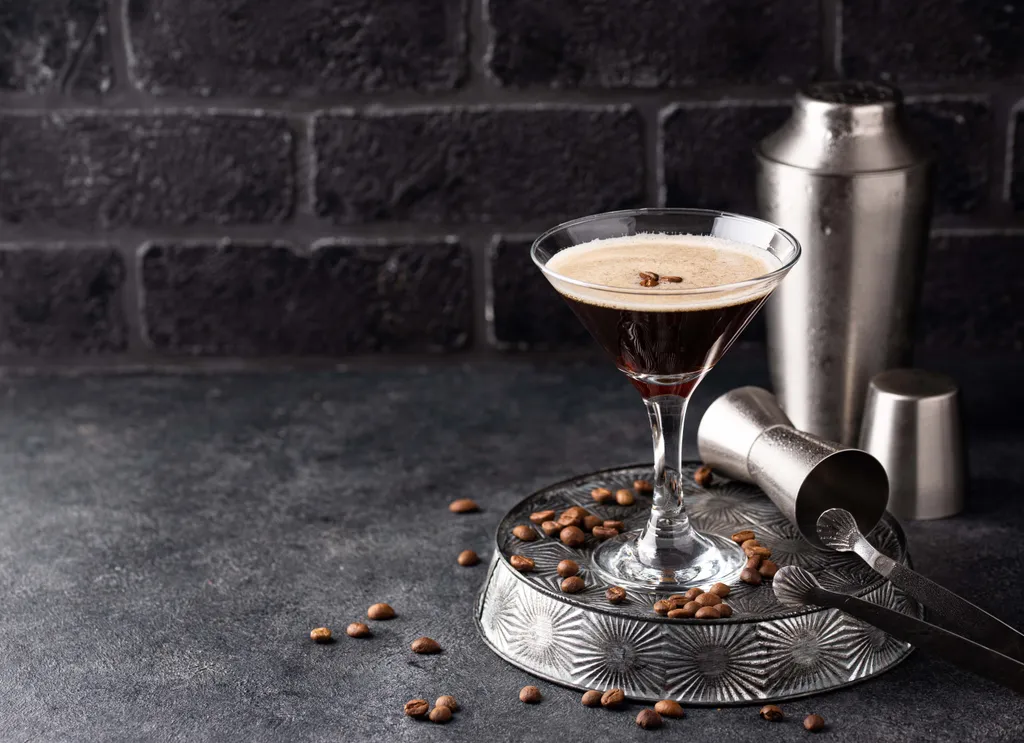 Espresso Martini im Cocktailglas mit Kaffeebohnen und Barzubehör