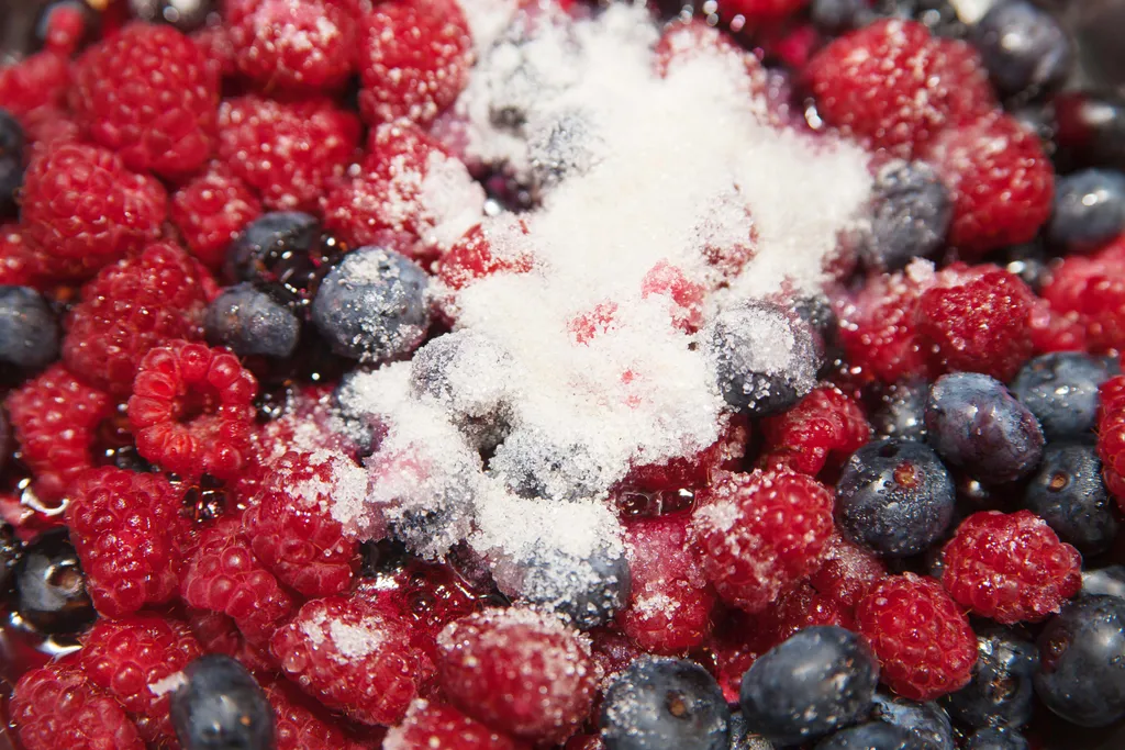Himbeeren und Heidelbeeren werden mit Gelierzucker bestreut