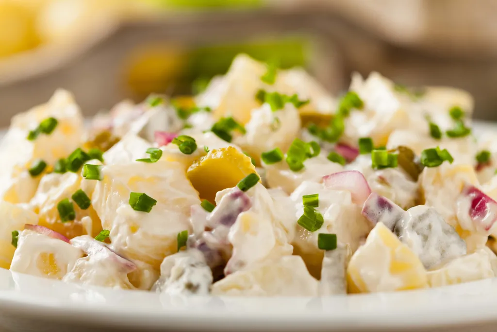 Ein Kartoffelsalat mit Mayonnaise, Schnittlauch, Zwiebeln und Kartoffeln in einem Teller