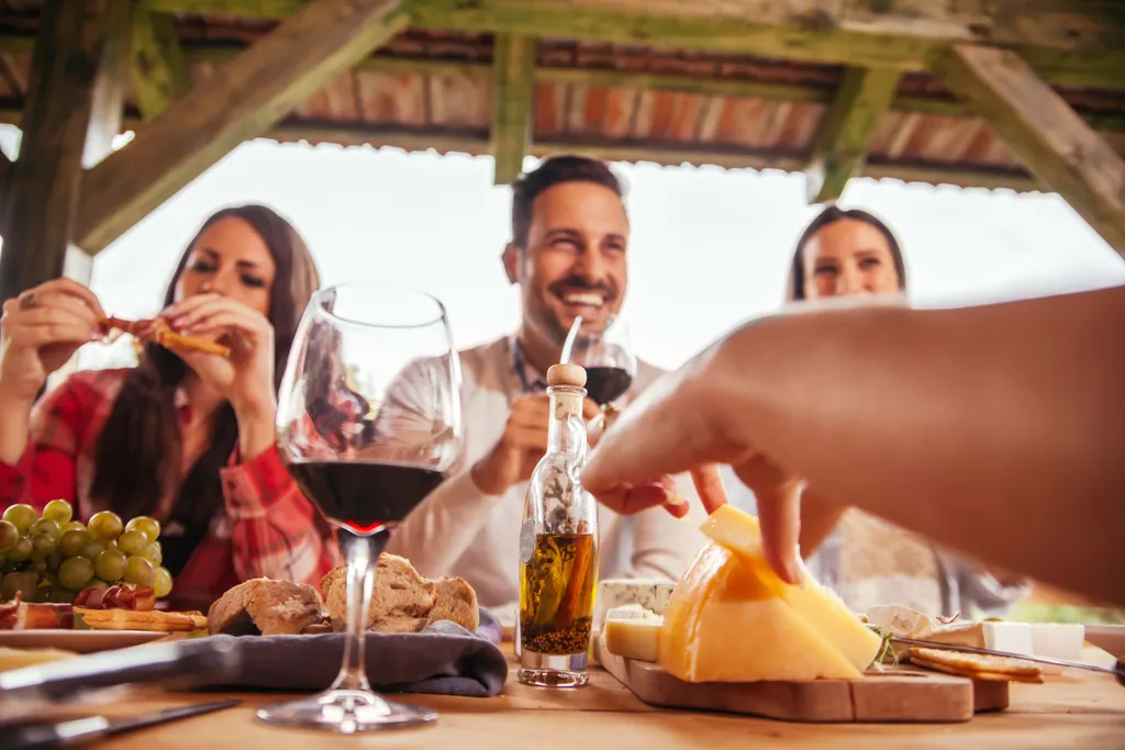 Mehrere Personen beim Essen von einer Käsejause mit Weinbegleitung