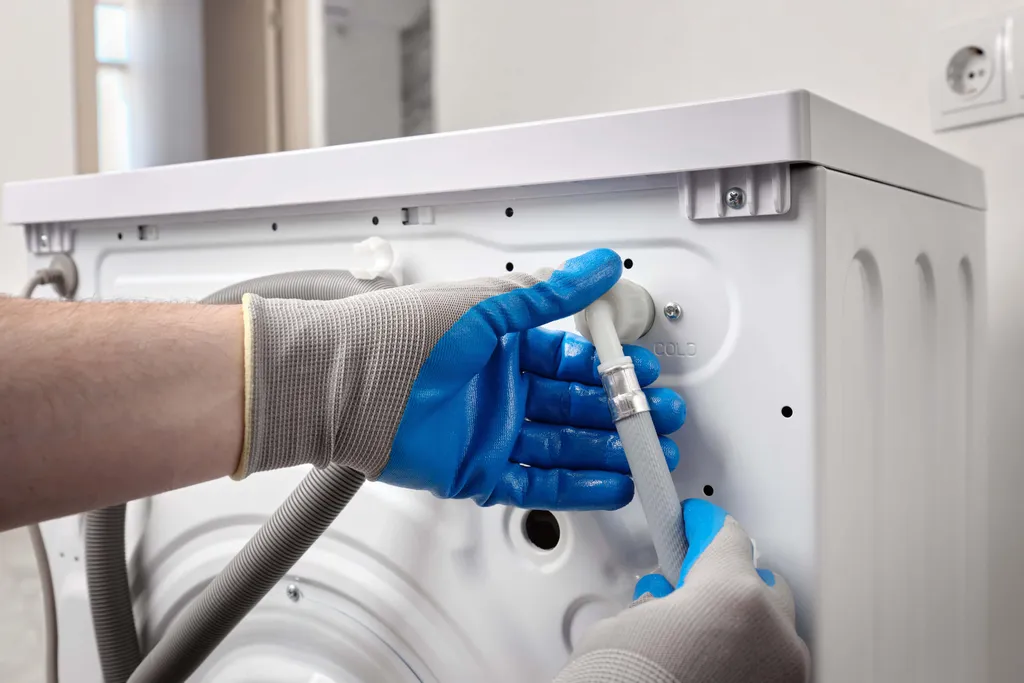 Handschuhe verbinden den Zulaufschlauch mit einer Waschmaschine