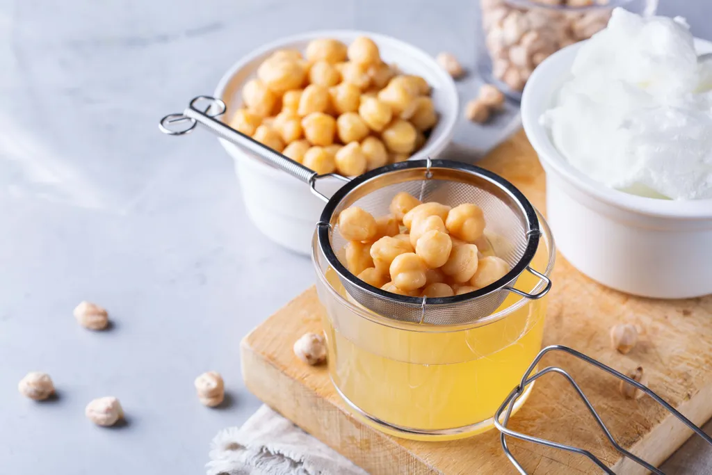 Aquafaba aus Kichererbsen wird durch ein Sieb in ein Glas gefiltert