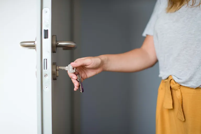 Person schließt eine Wohnungstür mit einem Schlüssel ab