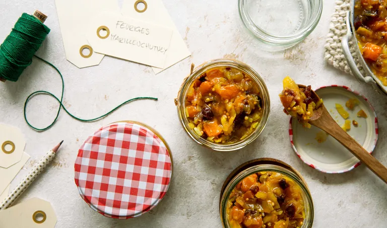 Würziges Marillenchutney in Einmachgläsern mit Aprikosen und Gewürzen von oben fotografiert