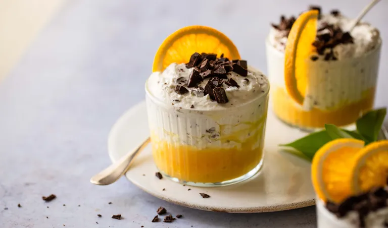 Cremige Topfencreme mit frischer Orange, Schlagobers und Zartbitterschokolade im Glas angerichtet