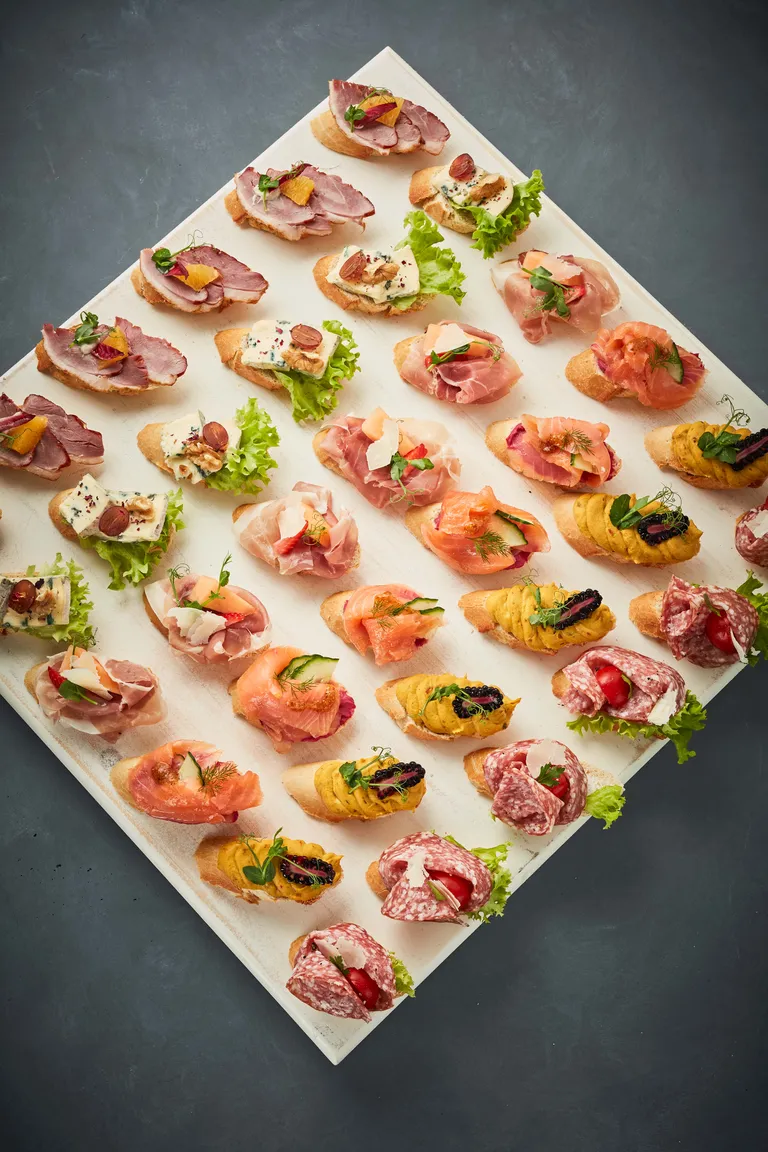 Nahaufnahme von Gourmet-Häppchen mit Blauschimmelkäse, Weintrauben, Walnüssen und Salat auf geschnittenem Brot.