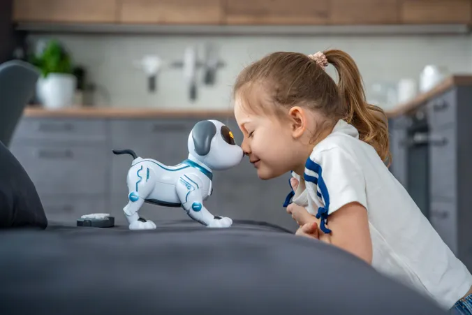 Mädchen berührt spielerisch einen interaktiven Roboterhund mit der Nase
