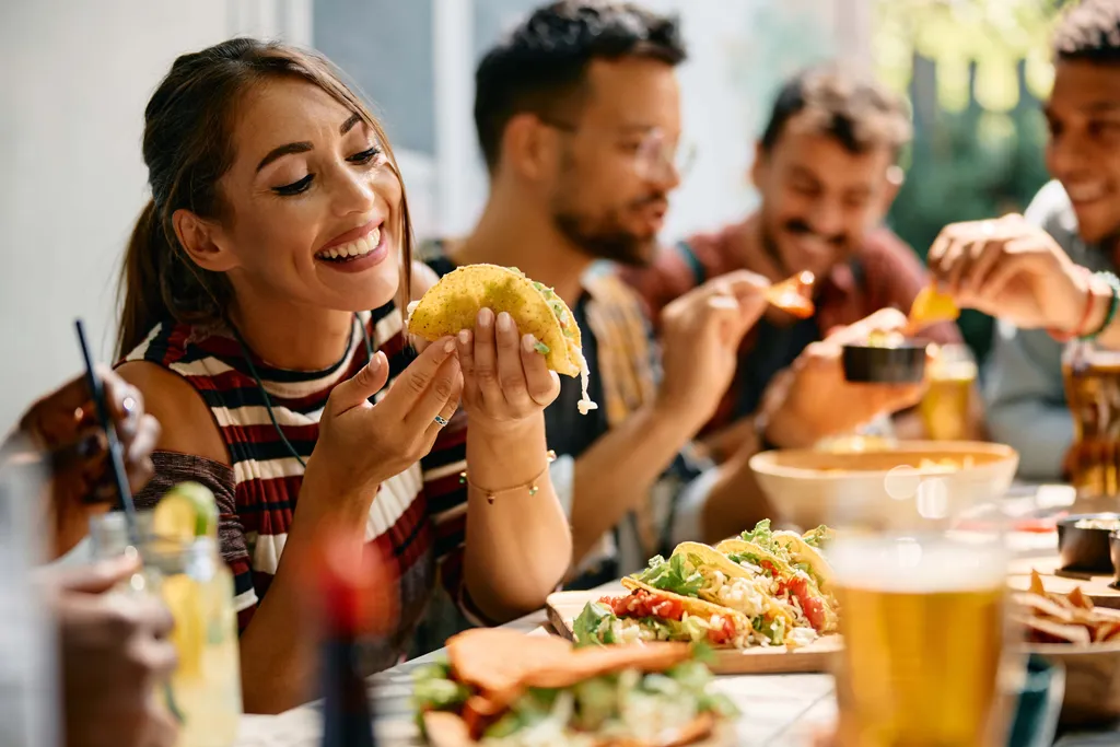 Freunde genießen gemeinsam Tacos und mexikanisches Essen in geselliger Runde