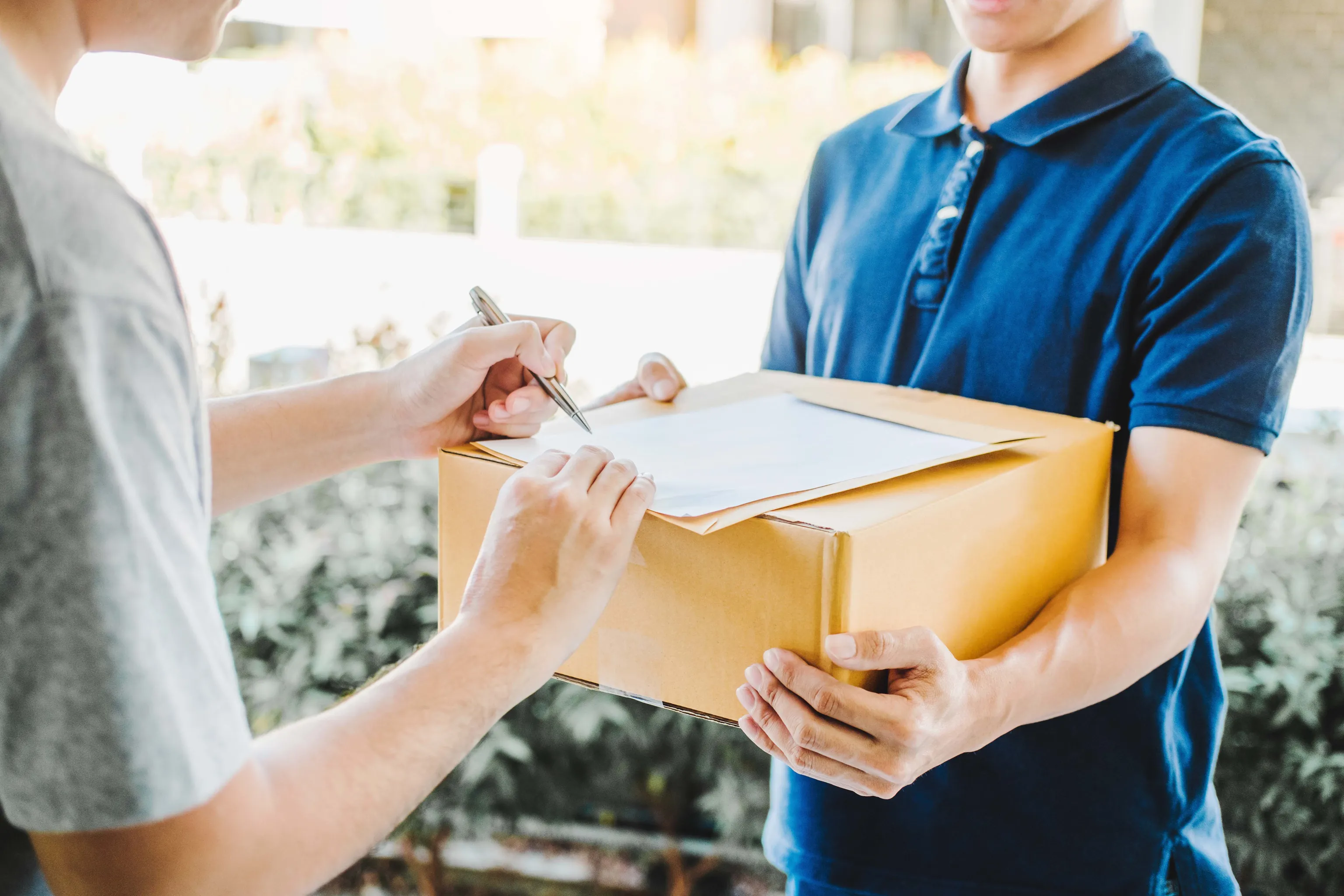 Paketbote übergibt ein Paket, das von der empfangenden Person unterschrieben wird
