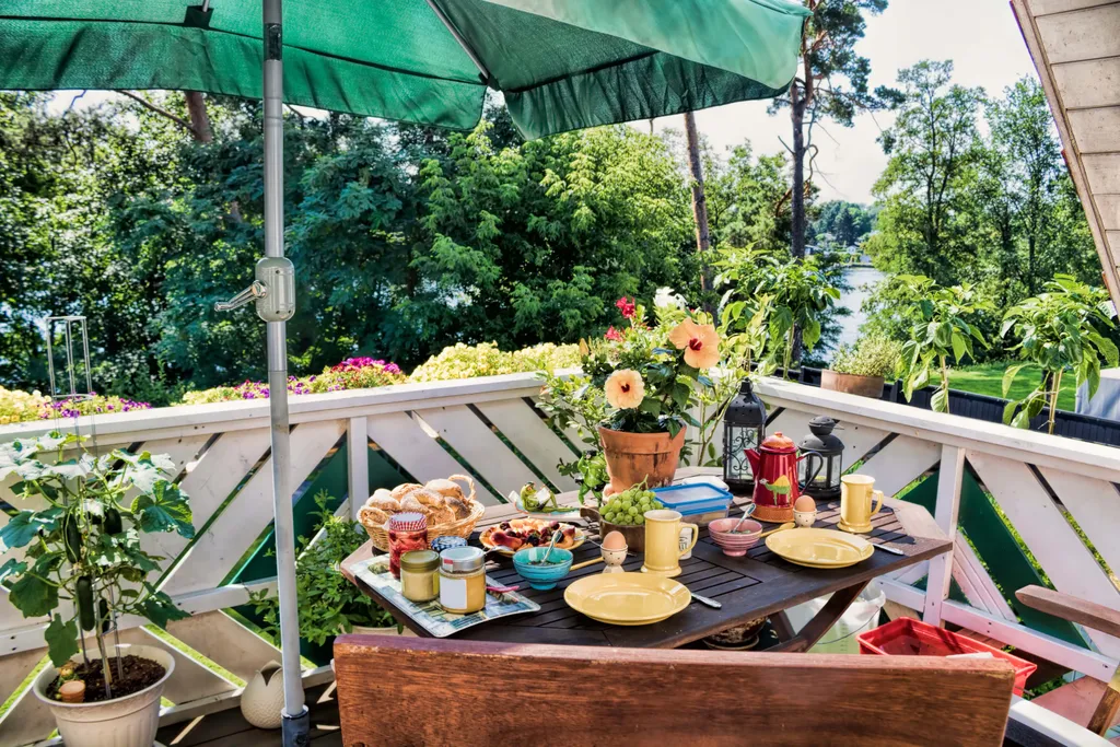 Frühstückstisch am Balkon mit grünem Sonnenschirm
