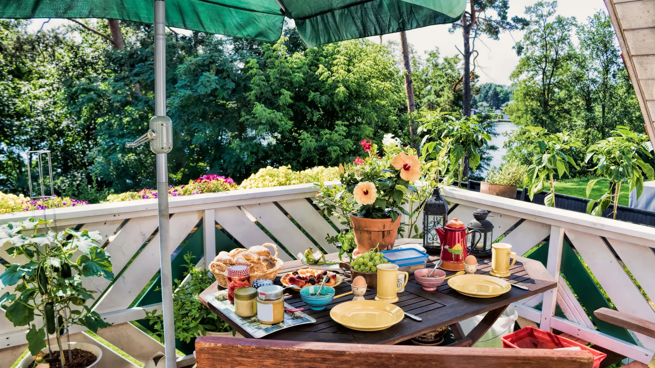 Frühstückstisch am Balkon mit grünem Sonnenschirm